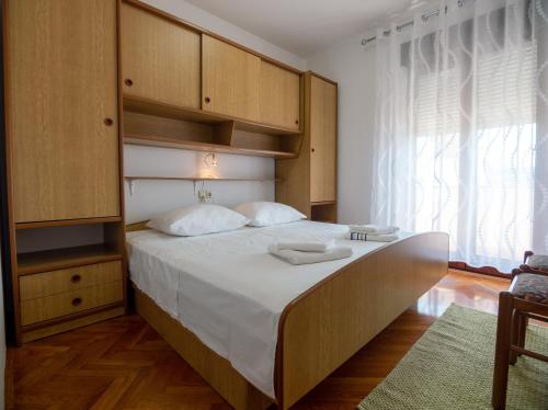 a bedroom with a large bed with wooden cabinets at Apartments Đoković in Rab