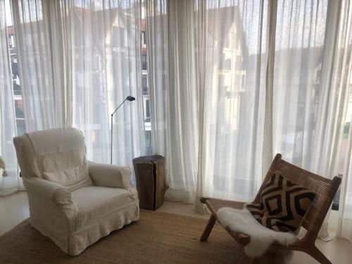 a living room with a white chair and a chair at Suite 133 hotel studio in Knokke-Heist