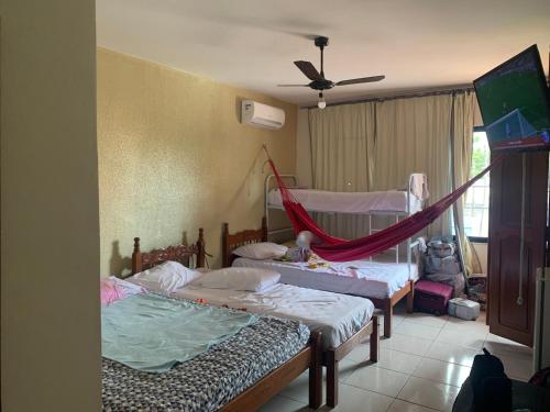 a room with two beds and a hammock in it at Pousada Malu in Fortaleza