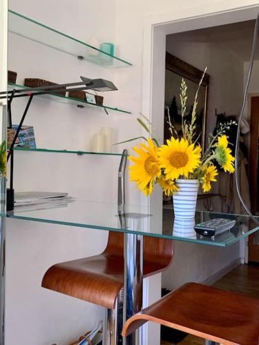 a glass table with a vase of yellow flowers on it at Mini Apartment in Öhningen