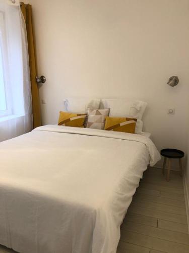 ein weißes Bett in einem Zimmer mit Fenster in der Unterkunft Alsacian Home - Old Town Cosy Apartments in Colmar