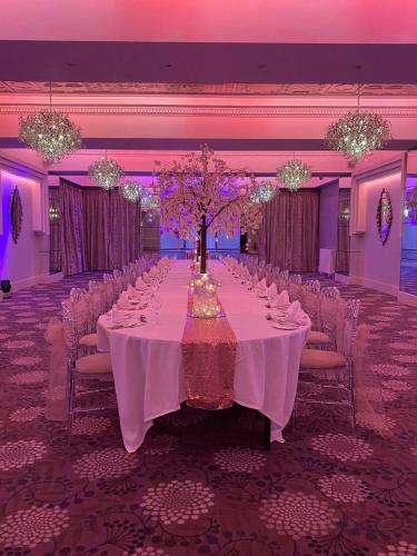 a long table in a banquet hall with white tables and chairs at Thornton Hall Hotel & Spa in Heswall