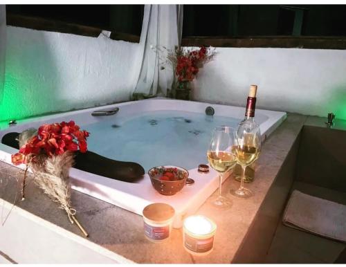 a bath tub with a bottle of wine and two glasses at Pousada Canto da Lua in Nova Lima
