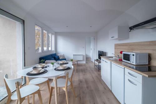 une cuisine et une salle à manger avec une table et des chaises blanches dans l'établissement Le Scandinave - Tarbes centre, à Tarbes