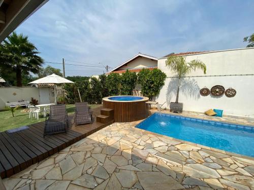 einen Pool mit einem Tisch und Stühlen neben einem Haus in der Unterkunft Casa Águas de São Pedro in Águas de São Pedro