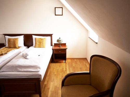 a bedroom with a bed and a chair in a attic at Hradná stráž Hotel&Apartments s privátnym wellness in Topoľčianky