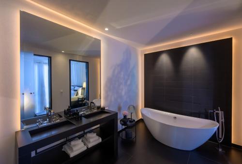 La salle de bains est pourvue d'une grande baignoire et d'un grand miroir. dans l'établissement A-ROSA Collection Hotel Ceres am Meer, à Binz