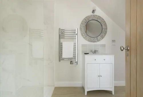 La salle de bains blanche est pourvue d'un lavabo et d'un miroir. dans l'établissement Stone Barn, contemporary barn conversion, à Cheltenham
