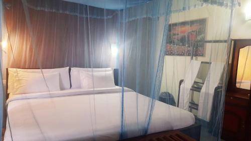 a bedroom with a large white bed with blue curtains at Sitha's Heaven in Ella
