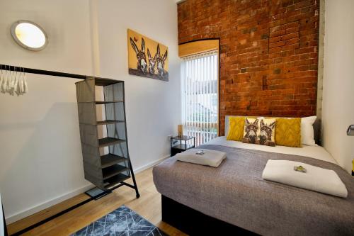 a bedroom with a bed and a brick wall at City Loft Apartment in Coventry