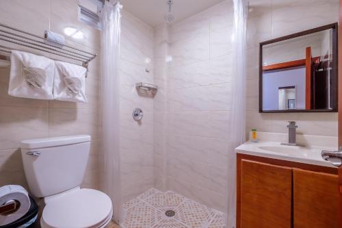 a white bathroom with a toilet and a sink at Voyager Sun & Reef Hotel in San Pedro