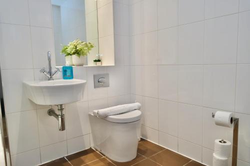 a white bathroom with a toilet and a sink at City Loft Apartment in Coventry