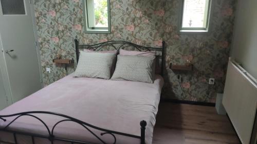 1 dormitorio con 1 cama con almohadas rosas y blancas en Vakantiewoning De Koolboet, en Koedijk