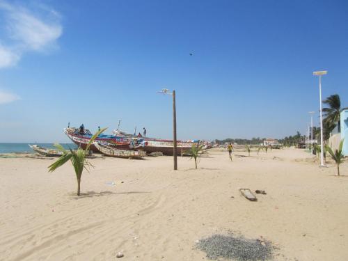 a sandy beach with a boat on the water at KEUR DIAM - Maison de la Paix in Saly Portudal