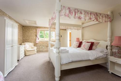 a bedroom with a white canopy bed with pink pillows at Stanton House, 6 bedroom, 5 bath in Cheltenham