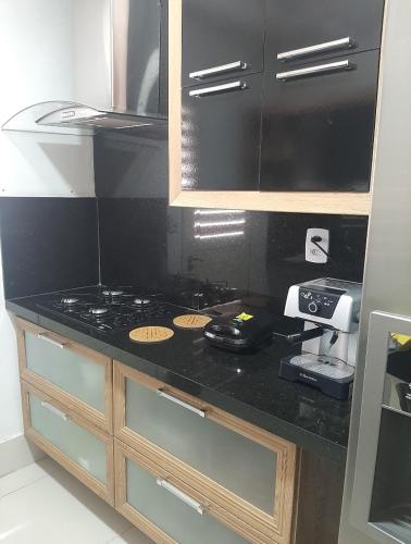 kuchnia z czarnym blatem z kuchenką w obiekcie FlatStudio02 em condomínio residencial na Nova Betânia w mieście Mossoró