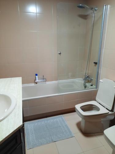 a bathroom with a tub and a toilet and a sink at Lujo y Paz en apartamento céntrico con piscina in Vigo