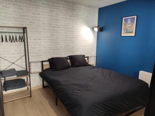 um quarto com uma cama com uma parede azul em L'Atelier de l'Artiste - Moulins Cœur de ville em Moulins