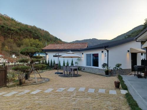 ein Haus mit einer Terrasse mit einem Tisch und einem Sonnenschirm in der Unterkunft Iryang Stay in Goseong