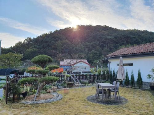 a patio with a table and an umbrella and a mountain at Iryang Stay in Goseong