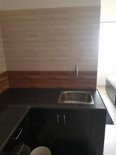 a kitchen with a sink and a black counter top at Anuraag in Bangalore