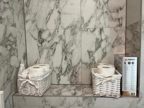 een badkamer met 2 manden en een marmeren muur bij Apartment Bjelasnica Mara in Bjelašnica