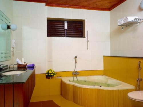 a bathroom with a tub and a sink and a toilet at Elephant Court Thekkady in Thekkady