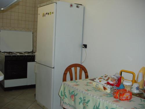 uma cozinha com uma mesa e um frigorífico branco em Residenza Del Sole em Surbo