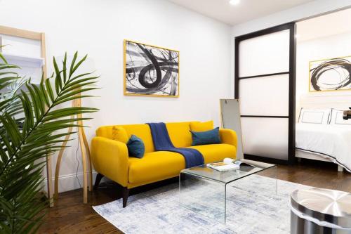 69-2D Stylish Lower East Side 1BR Apt BRAND NEW في نيويورك: أريكة صفراء مع وسائد زرقاء في غرفة المعيشة