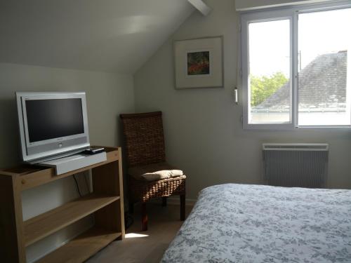 a bedroom with a bed and a tv and a chair at Chambre et salon sur la Loire à vélo in Les Ponts-de-Cé