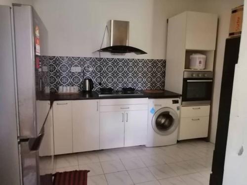 a kitchen with a refrigerator and a washing machine at Cozy house with free wifi and parking near Utm, Legoland in Skudai