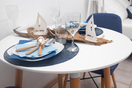 a white table with a table set with plates and glasses at Le petit marin des salines à 0 metre de la plage in Montjoly