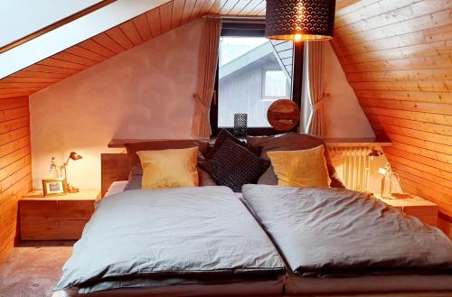 a bedroom with a large bed with a window at Traum-Maisonette auf 1.000m mit Pool und Sauna in Schönwald