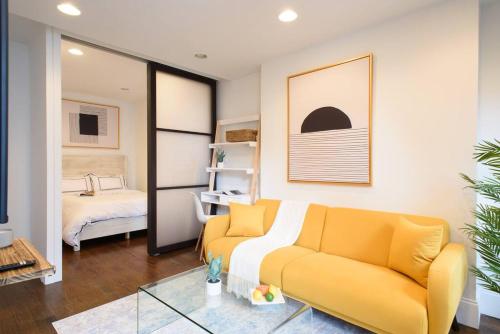a living room with a yellow couch and a bedroom at 69-5A Modern Lower East Side 1BR Apt BRAND NEW in New York