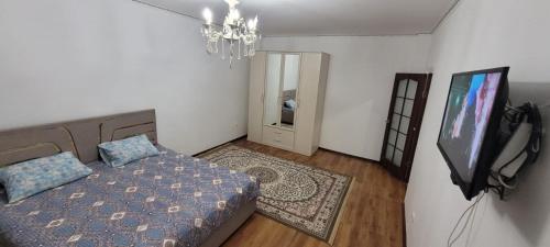 a bedroom with a bed and a flat screen tv at Квартира in Atyraū
