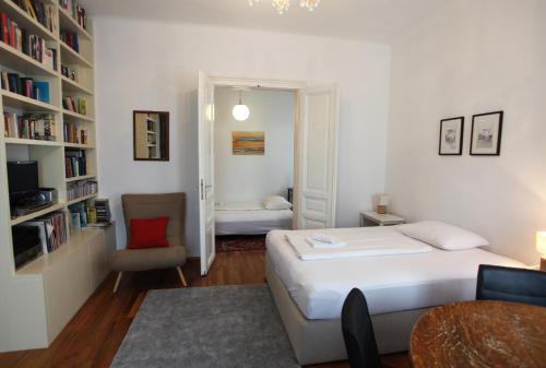 a bedroom with a bed and a chair and a book shelf at Casa Nostra - Ausgefallene Wohnung am Augarten in Vienna