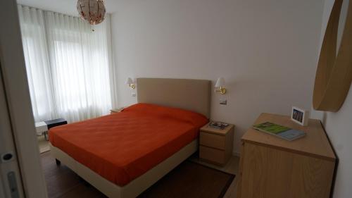 um pequeno quarto com uma cama com uma colcha laranja em Danae Home em Milão