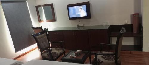 a living room with a television and a table and chairs at Hira Guest House in Karachi
