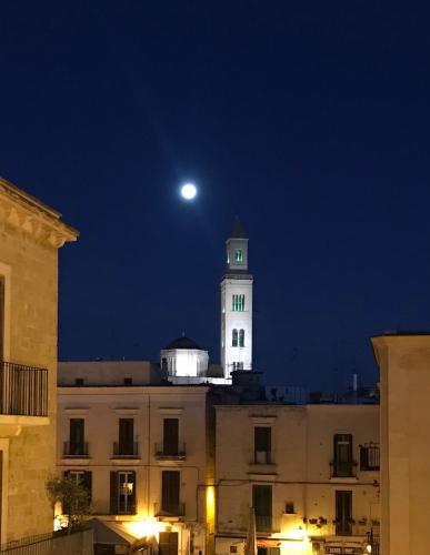 a moon over a building with a clock tower at night at B&B Via dell'Azzurra in Bari