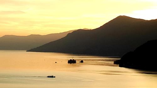 a boat in the water in front of a mountain at Sole & Lago-Lake in Maccagno con Pino e Veddasca