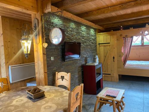 a dining room with a table and a clock on a stone wall at Chalet d' Annelise in Gérardmer