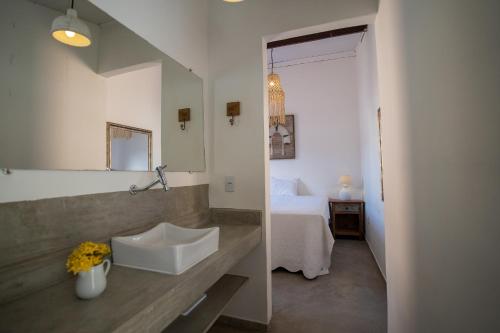 a bathroom with a sink and a bedroom with a bed at Arandu Casa Hotel Quadrado in Trancoso