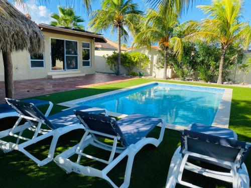 two chairs and a swimming pool in front of a house at Villa Mi Dushi Cas Aruba in Palm-Eagle Beach