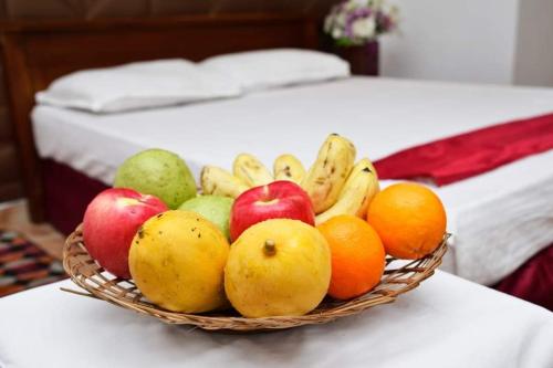a basket of fruit on a table next to a bed at Silent Peacock Villa And Peacock Cafe in Tangalle
