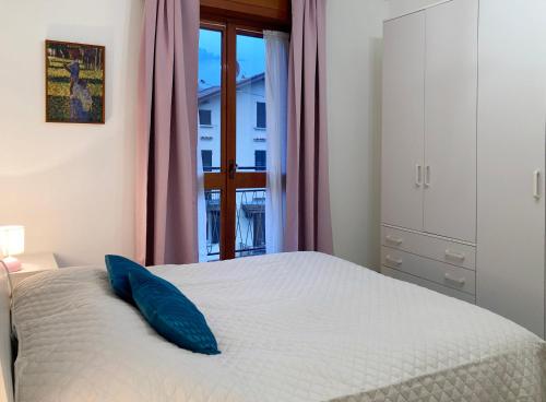 um quarto com uma cama com almofadas azuis e uma janela em Bellavista - Residence in Barzio center near free ski shuttle em Barzio