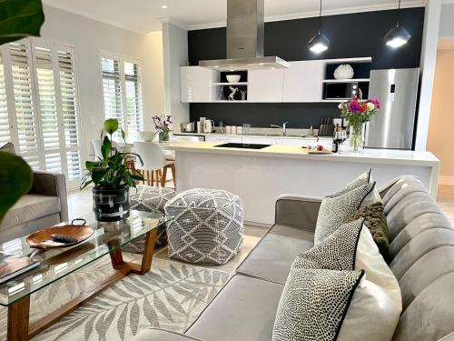 a living room with a couch and a kitchen at The Village Cottage in Franschhoek