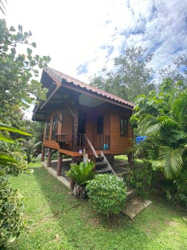 a wooden house with a porch in a garden at Mookdaman Bungalow in Ko Yao Noi
