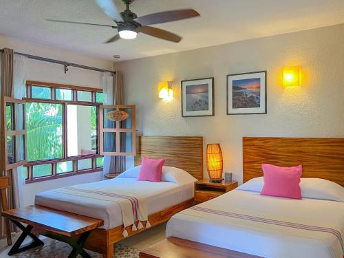 a bedroom with two beds with pink pillows at Hotel Hulku in Playa del Carmen