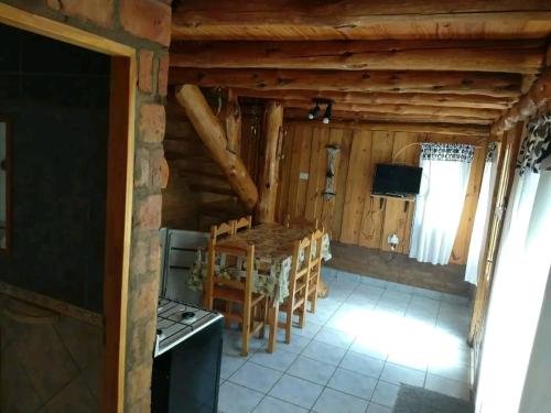 una cocina con mesa y sillas en una cabaña en Murmullos del bosque en Lago Puelo