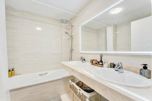 La salle de bains est pourvue de 2 lavabos, d'une baignoire et d'un miroir. dans l'établissement Black Beach Luxury Vacation House, à Puerto de Santiago